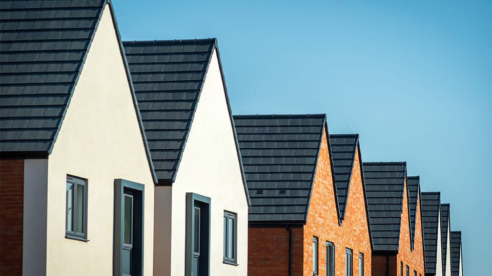 A group of newly built houses with blue sky in background